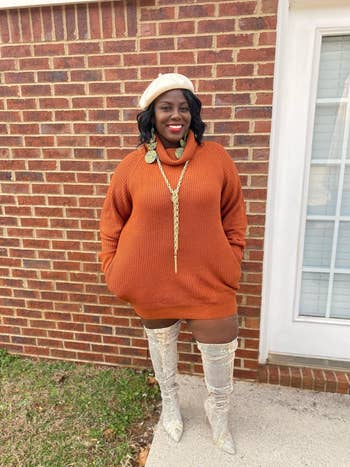 reviewer posing in orange sweater dress with accessories