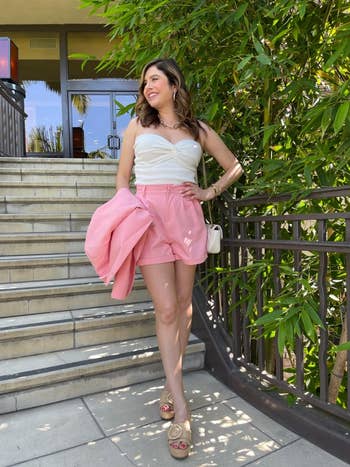 reviewer wearing the pink shorts while holding the pink blazer