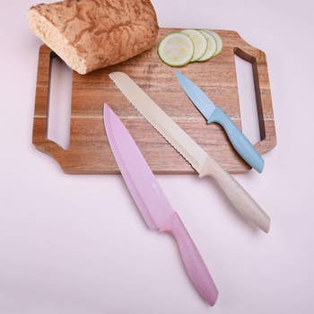 three of the pastel knives on a cutting board