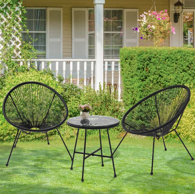 black bistro set with two circular chairs and one table in the middle