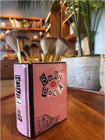 the burn book box being used to hold makeup brushes