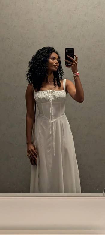 Person taking a reflector  selfie wearing a stylish, sleeveless formal  with a tied beforehand   detail