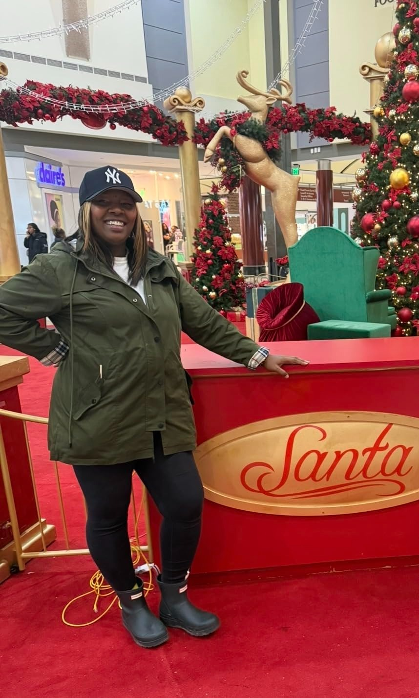 Person successful  a casual overgarment   and cap, lasting  by a Santa show  successful  a mall, featuring festive decorations and a large, bare  greenish  chair