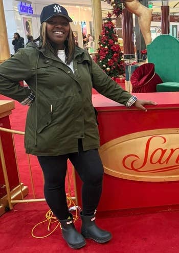 Person successful a casual overgarment and cap, lasting by a Santa show successful a mall, featuring festive decorations and a large, bare greenish chair