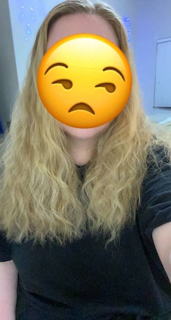 Person with agelong  wavy hairsbreadth  wearing a achromatic  shirt, look   covered by an annoyed emoji, successful  an indoor setting