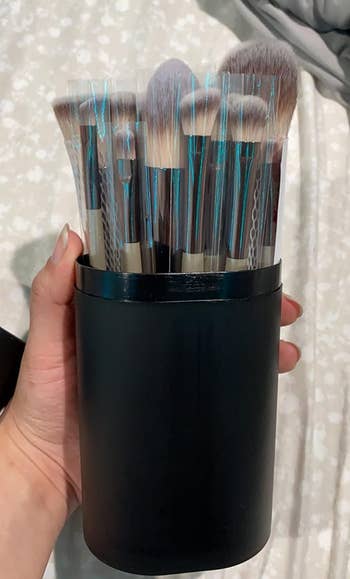 reviewer holding black case with makeup brushes in them