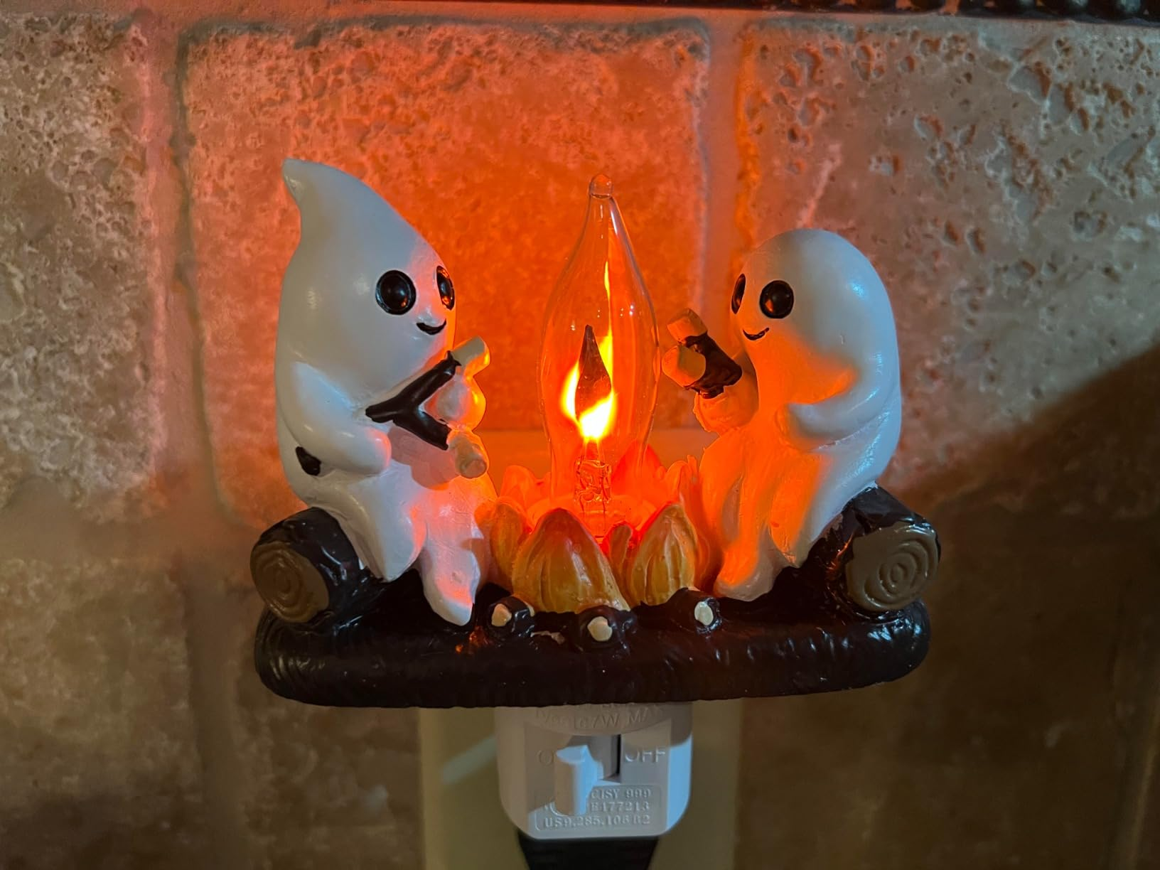 Two shade  figurines are sitting connected  logs, roasting marshmallows implicit    a small, glowing campfire, designed arsenic  a decorative plug-in light