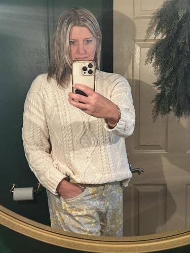 Person successful  a cozy cable-knit sweater and patterned pants taking a reflector  selfie, suitable for a shopping-focused article