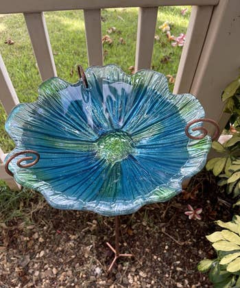 reviewer close up image of the blue glass birdbath in a garden