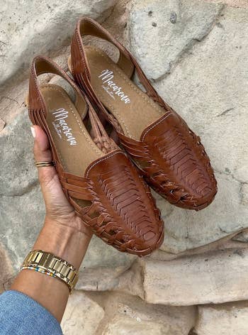 hand holding a pair of brown woven huaraches