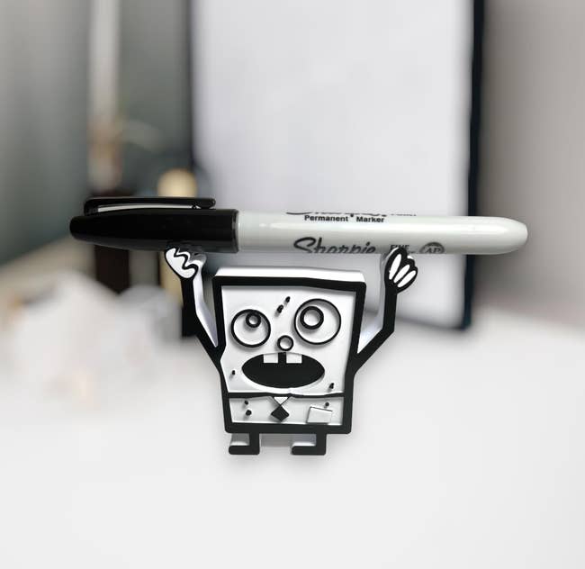 A creative stand holding a marker designed to look like a character with arms and a surprised facial expression
