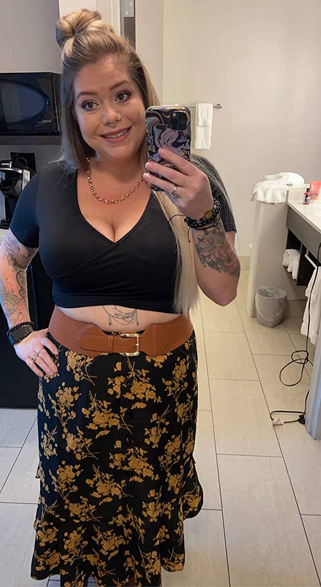 Reviewer is wearing a black skirt with a gold floral pattern and a black top