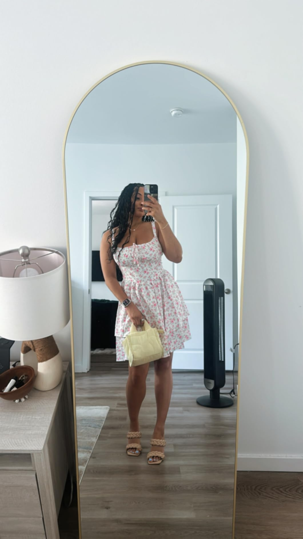 Person takes reflector  selfie successful  a floral dress, holding a airy  purse, lasting  successful  a modern   country   with minimal decor and a lasting  instrumentality   visible