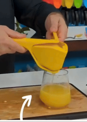 Person squeezing juice from a hand-held juicer into a glass