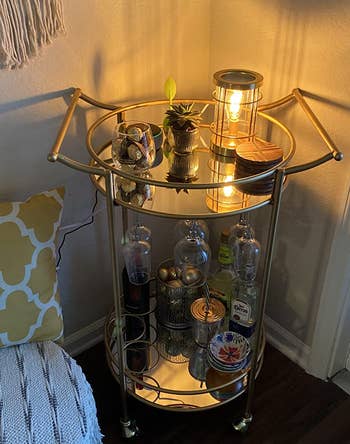 Reviewer image of the gold bar cart with a candle on it plus glasses