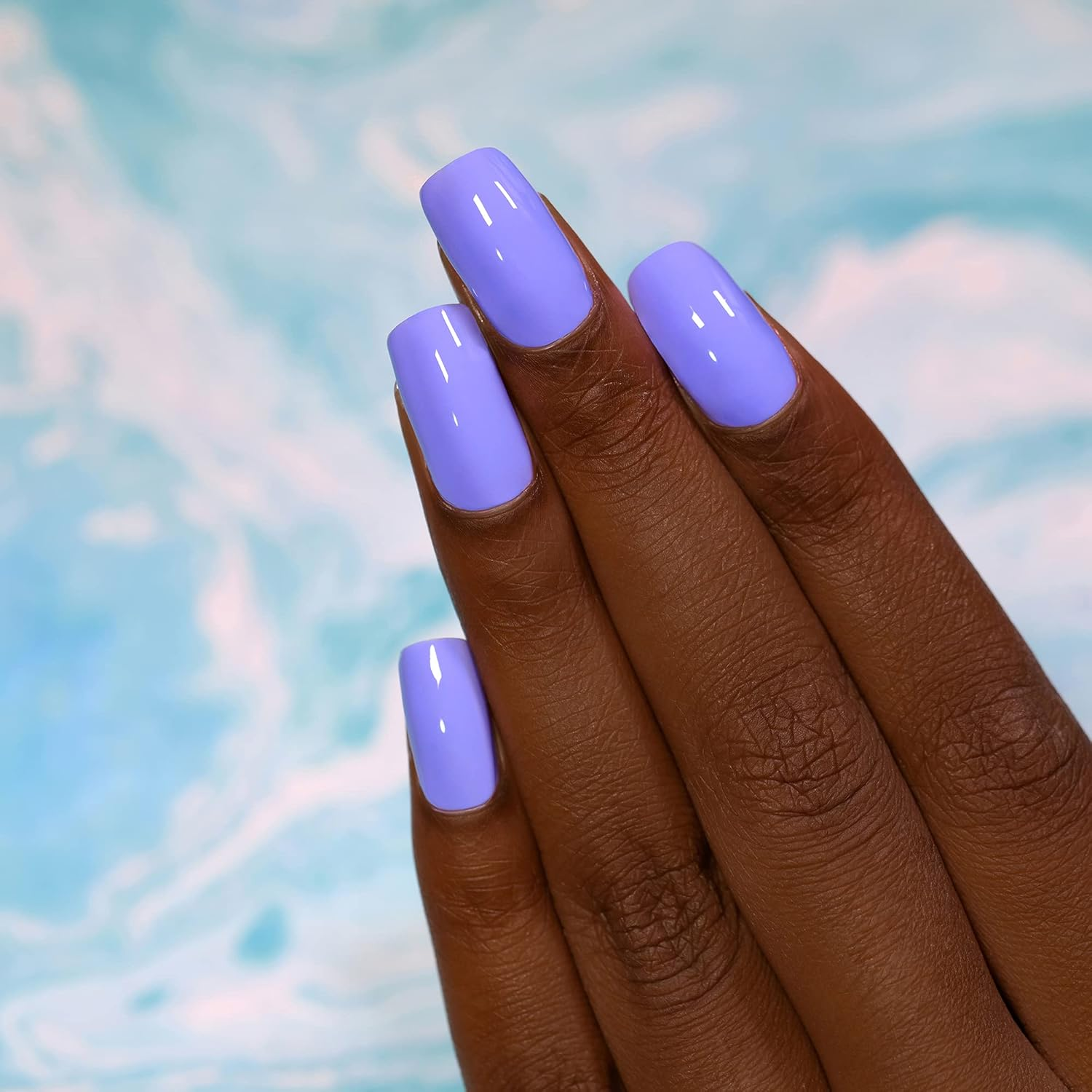 Close-up of a manus  with long, glossy, pastel purple nails against a marbled background