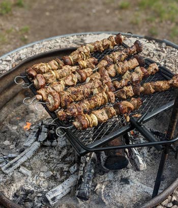 reviewer photo of pieces of meat on the skewers being cooked over a fire
