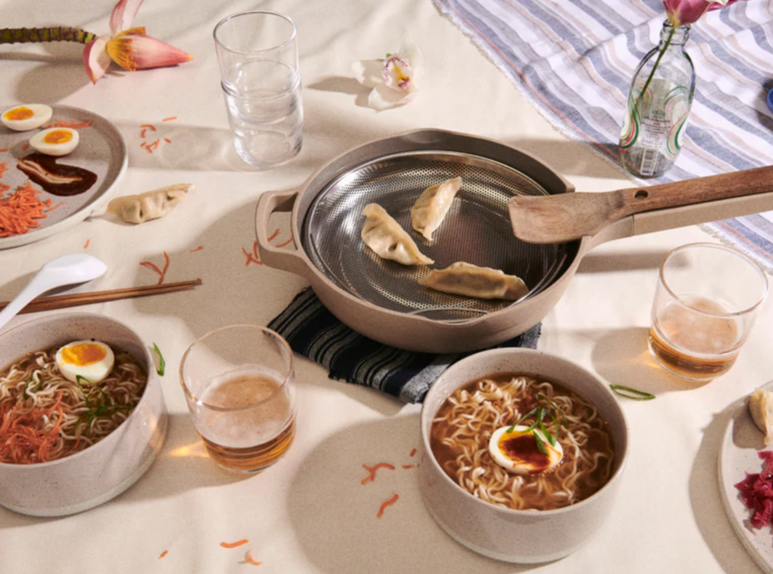 photo of  the always pan with steamed dumplings in it on a table surrounded by bowls of ramen