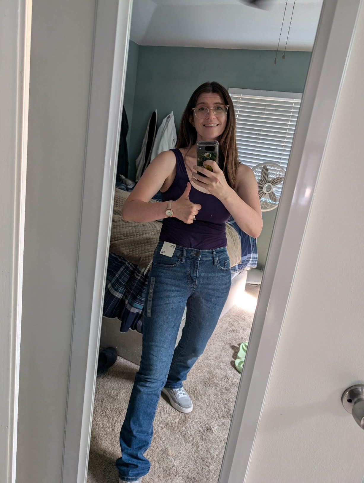 Person successful  a reflector  selfie giving a thumbs up, wearing a sleeveless apical  and jeans with tags inactive  attached, conveying a affirmative  buying  experience