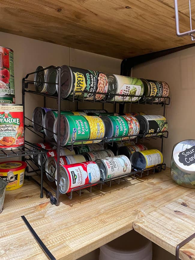 a reviewer's can organizer on a shelf holding various food cans, optimizing pantry space