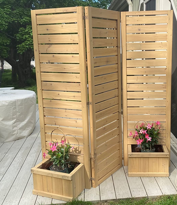 reviewer photo of the planter privacy wall holding pink flowers