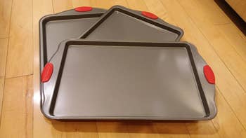 a reviewer's three baking sheets with red silicone handles