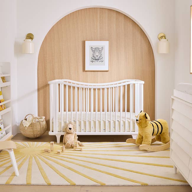 Rectangular rug with sun pattern placed on nursery floor beside yellow toys