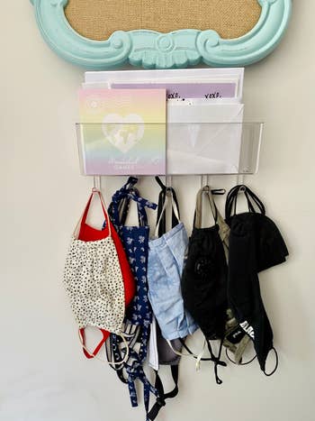 the clear acrylic mail holder with mail inside and masks hanging on the hooks