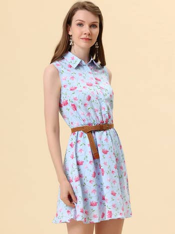model in light blue sleeveless mini shirtdress with pink flowers and brown braided belt