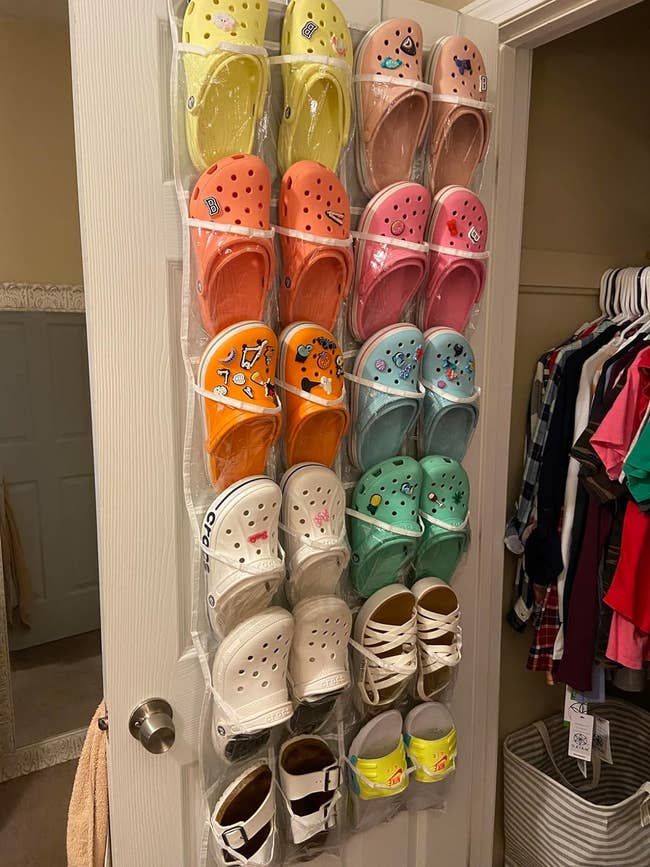 reviewer's gray shoe holder hanging on a closet door holding several pairs of Crocs