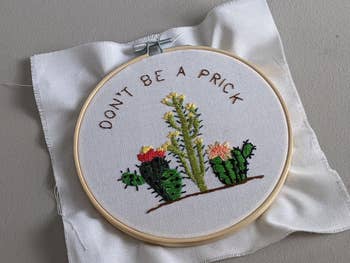 embroidery with wooden wheel with three cacti that says don't be a prick