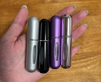 reviewer photo of them holding four atomizers in gray, black, purple, and chrome