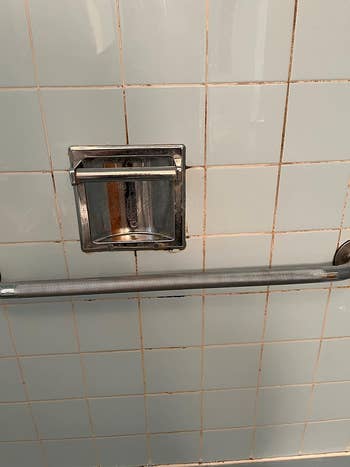 reviewer's shower wall with moldy, stained grout