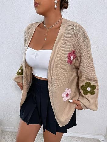 a model wearing the cardigan in tan with multicolor flowers on it