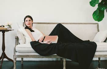 a model lounging on a couch under the black blanket 