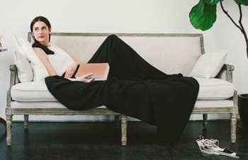 a model lounging on a couch under the black blanket 