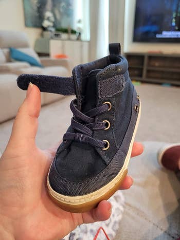 reviewer holding a toddler's shoes that are laced with the elastic no-tie laces