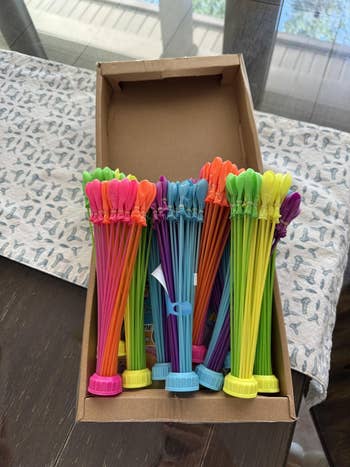 Box of colorful h2o  balloon bunches with attached capable    hoses connected  a tablecloth
