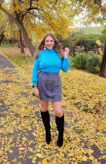 another reviewer wearing the skirt with a turquoise turtleneck and high boots