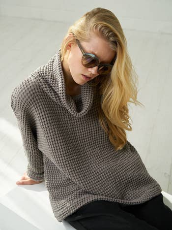 A model wearing the chunky linen sweater in gray, paired with loose black pants