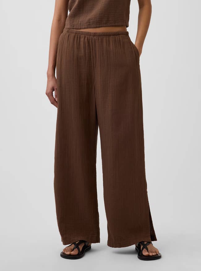Person wearing loose, textured brownish  pants with an elastic waistband and achromatic  sandals, lasting  casually