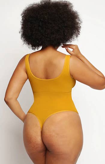 model showing the thong backside of the yellow bodysuit