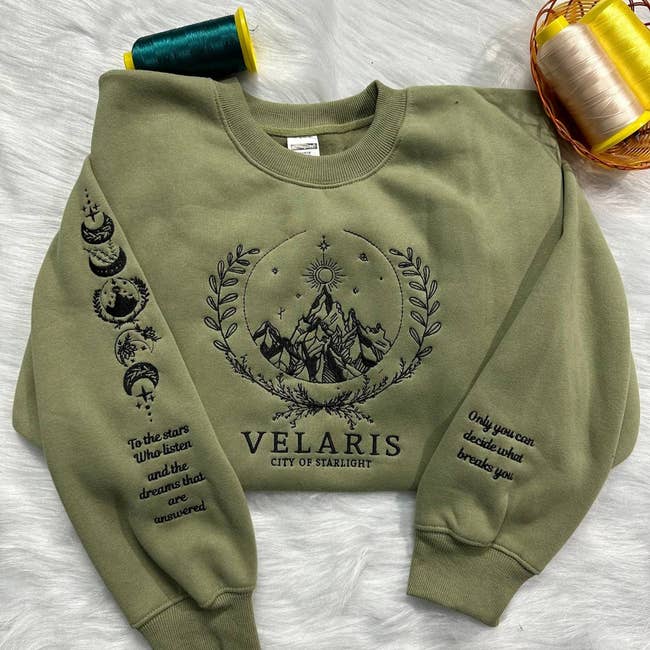 Green sweatshirt featuring upland plan with celestial symbols, inspirational substance astir dreams and resilience, and the connection