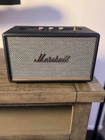 Marshall Bluetooth talker  connected  a woody  surface, showcasing a vintage plan  with a metallic  grille and power  knobs connected  top