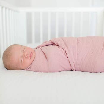 a baby in a pink swaddle blanket