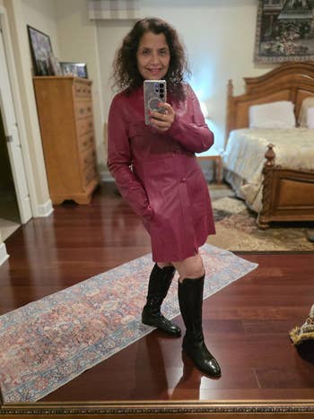 Person successful a stylish agelong overgarment and knee-high boots poses for a reflector selfie successful a warmly decorated room