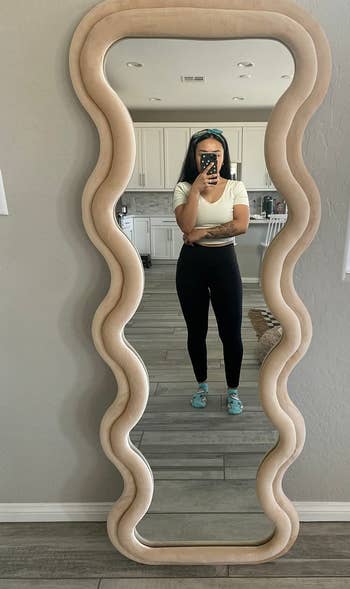 Person in a mirror selfie wearing a cropped top, leggings, and sneakers, suitable for fitness or casual wear