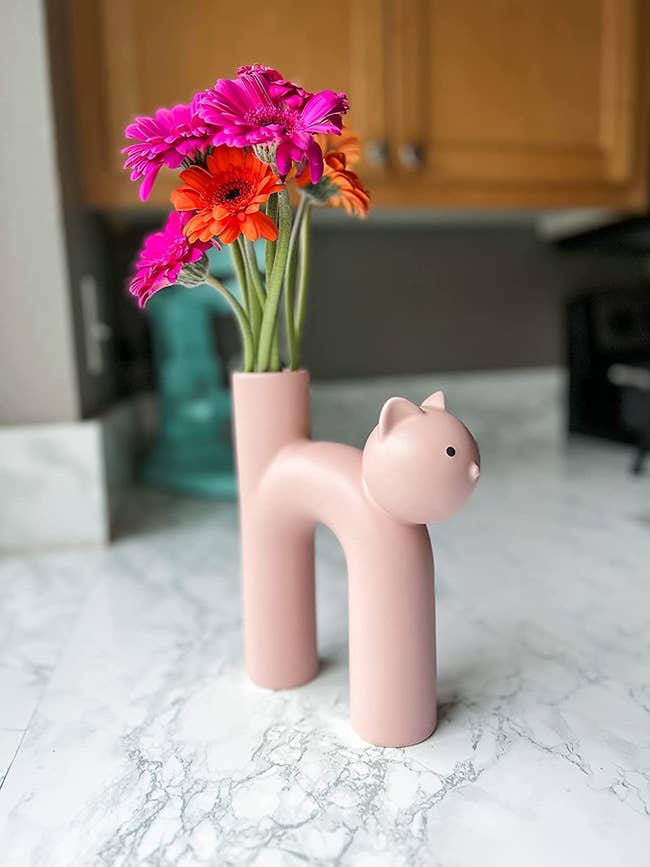 reviewer showing a light pink slim vase showing colorful flowers