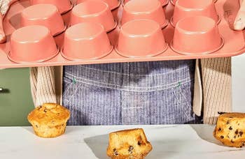 Person successful apron holds a non-stick muffin tray with baked muffins. Text highlights non-toxic, aluminized alloy assemblage for healthier baking