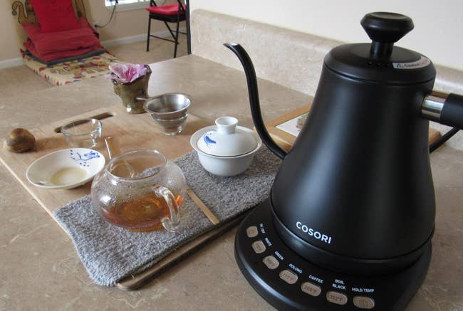 a reviewer shows the black kettle and tea made with it